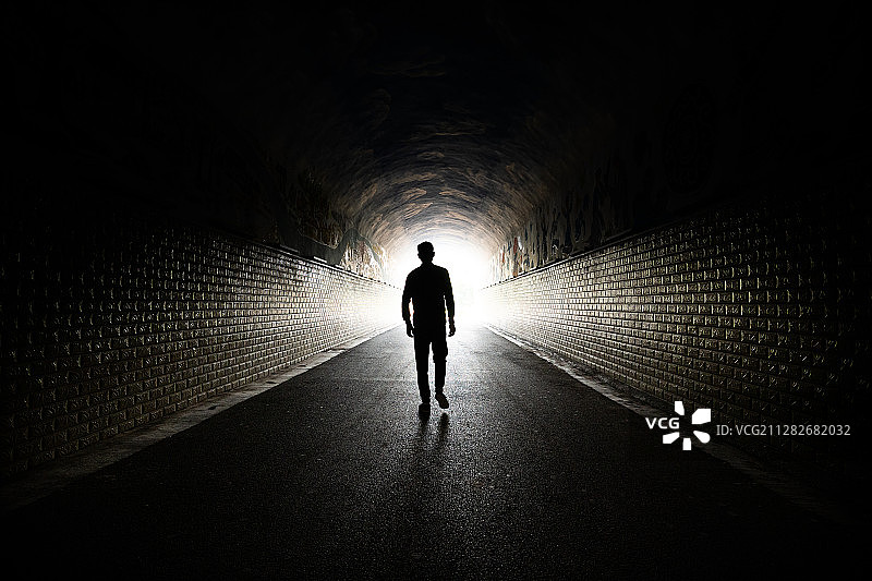 一个男人从黑暗的通道里走向光明图片素材