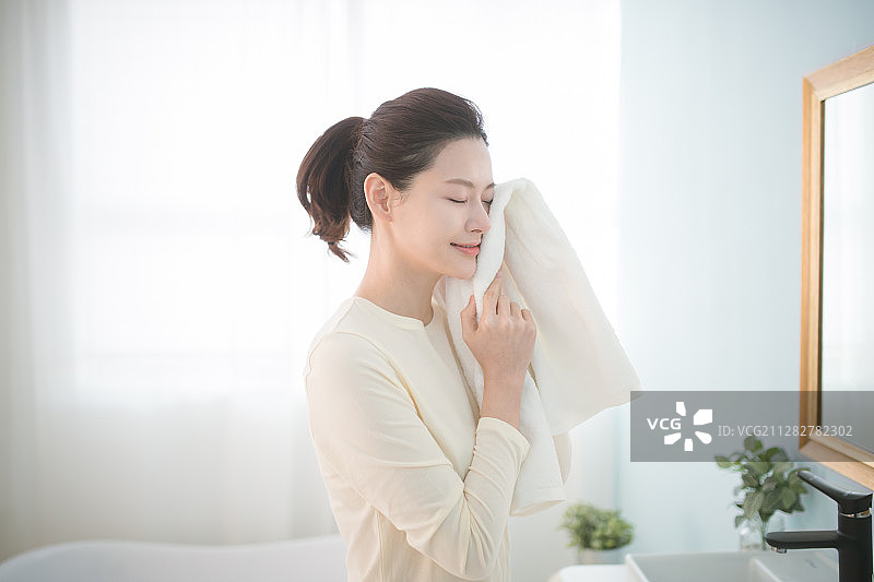 在浴室用毛巾擦脸的女人照片图片素材