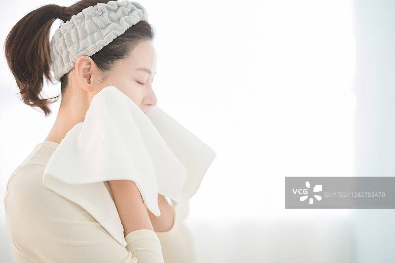 在浴室里用毛巾擦脸的女人照片图片素材