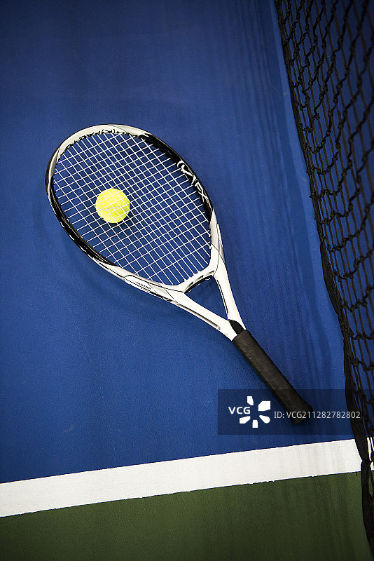 网球场上球网旁边的网球和球拍照片图片素材
