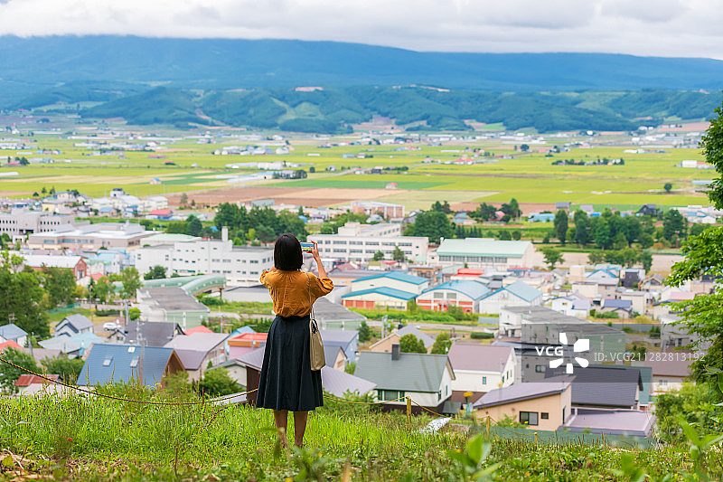 用手机拍摄日本北海道富良野乡村田园的女青年图片素材