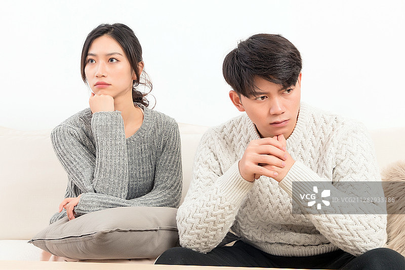 一对漂亮的亚洲年轻情侣坐在沙发上吵架图片素材