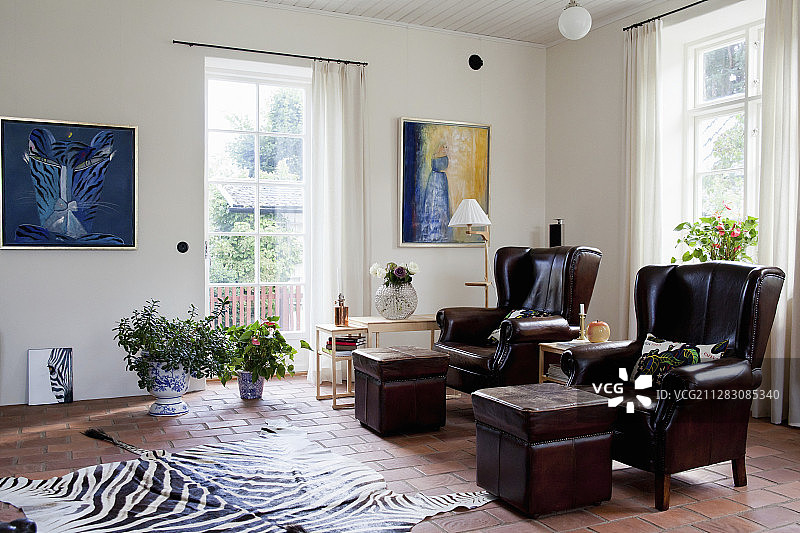 客厅里带脚凳的两张深棕色皮扶手椅图片素材