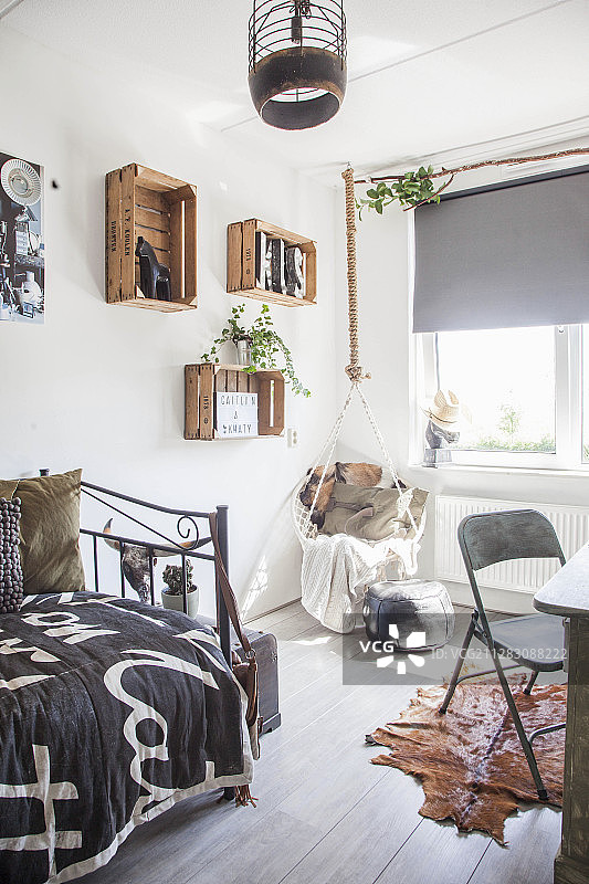 青少年卧室：悬挂椅、旧酒箱搁架和金属床图片素材