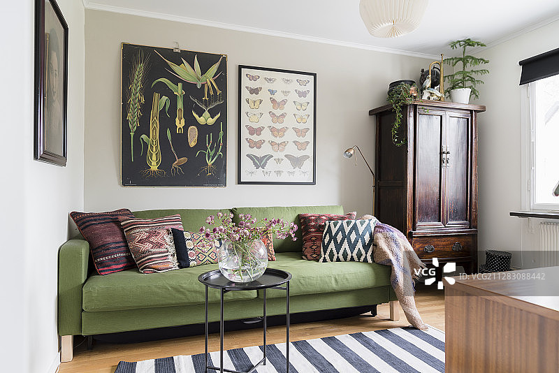 客房内带靠垫和中式柜子的绿色沙发床图片素材