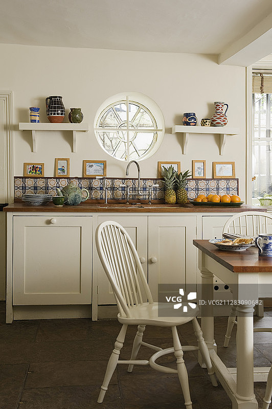 简约乡村厨房：白色家具与圆形窗户图片素材