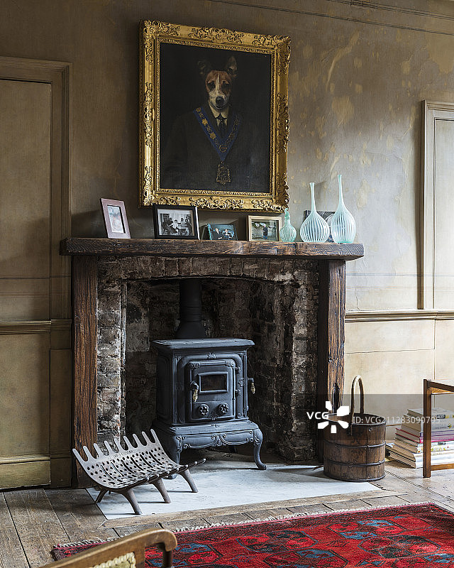 古董壁炉上方，镀金相框异想天开的狗画像图片素材