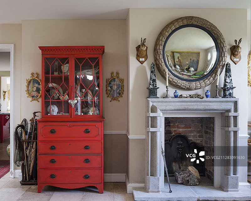 壁炉上方圆形镜子旁的红色桃花心木梳妆台图片素材