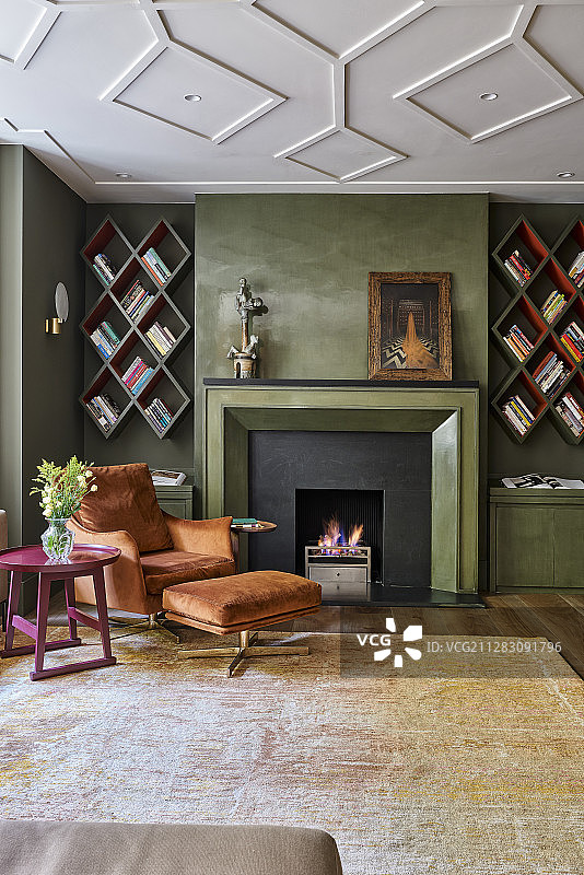 壁炉旁的扶手椅和脚凳以及菱形书架图片素材
