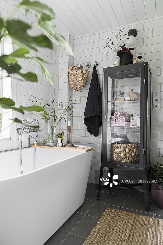 现代独立式浴缸旁的黑色展示柜图片素材