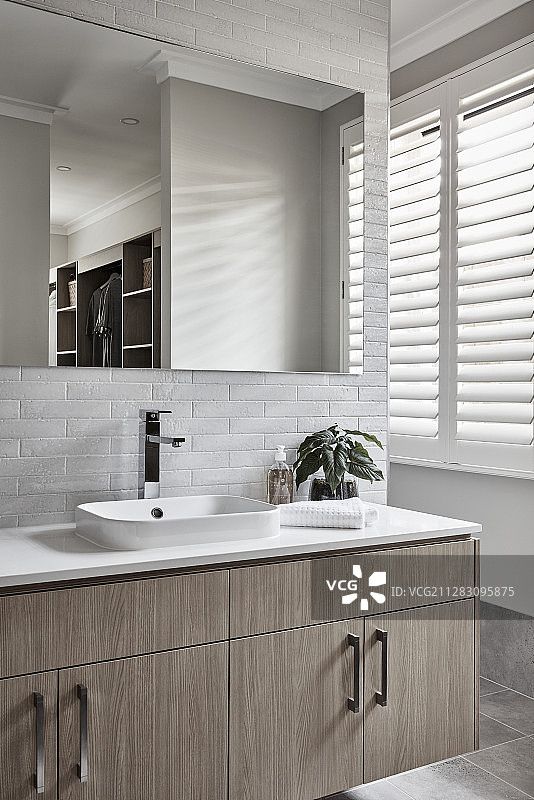 带台面水槽和镜子的洗手台，背景为白色砖墙图片素材