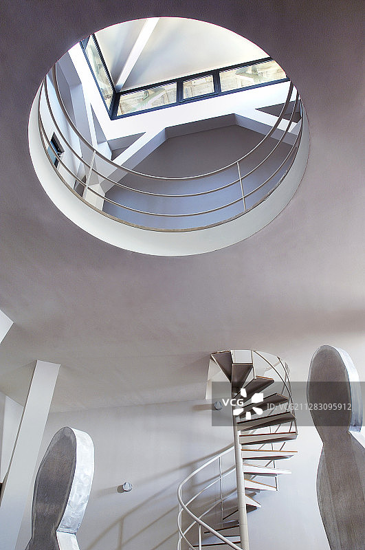 阁楼公寓内的螺旋楼梯和艺术品，天窗下有圆形开口图片素材