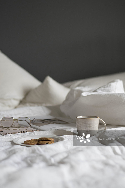 床上的饼干、马克杯、书和眼镜图片素材