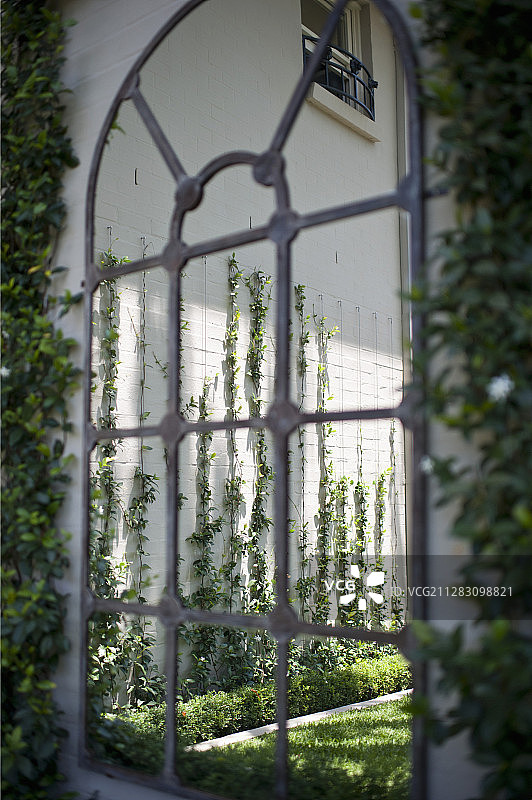 花园墙壁上的拱形铁窗框图片素材