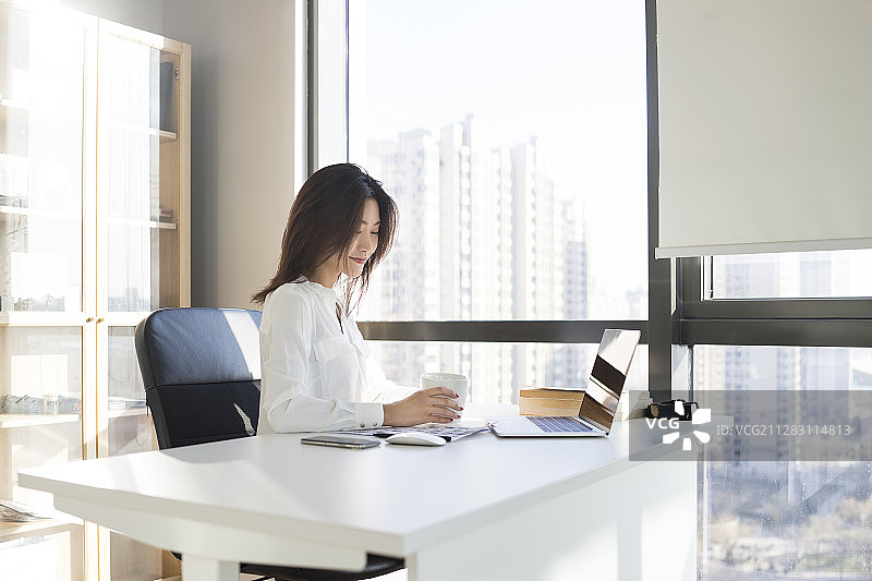 年轻商务女士在办公室喝咖啡图片素材