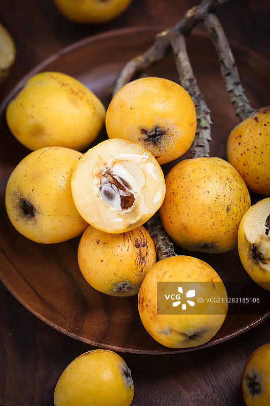 新鲜多汁的枇杷放在黑胡桃木盘子上图片素材