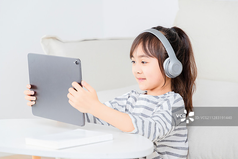 坐在地毯上玩平板电脑的亚洲小女孩图片素材