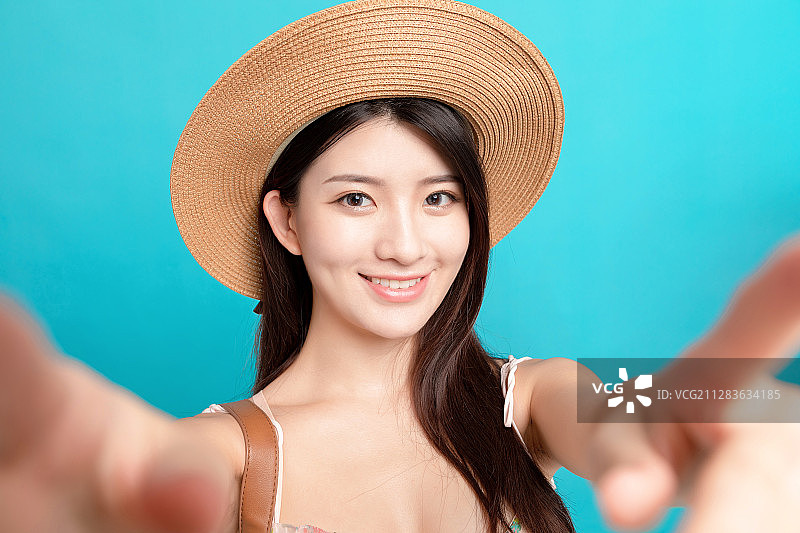 蓝色背景里，自拍的亚洲女孩图片素材