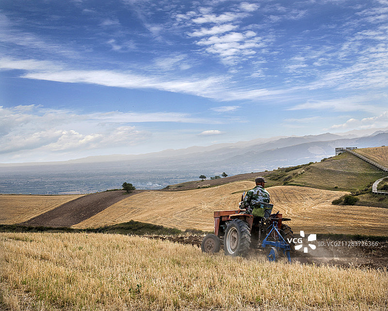 新疆奇台县江布拉克景区麦田中耕地的拖拉机手图片素材