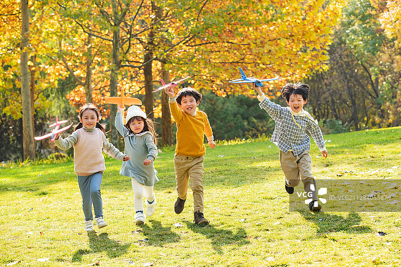 拿着玩具飞机在公园玩耍的快乐儿童图片素材