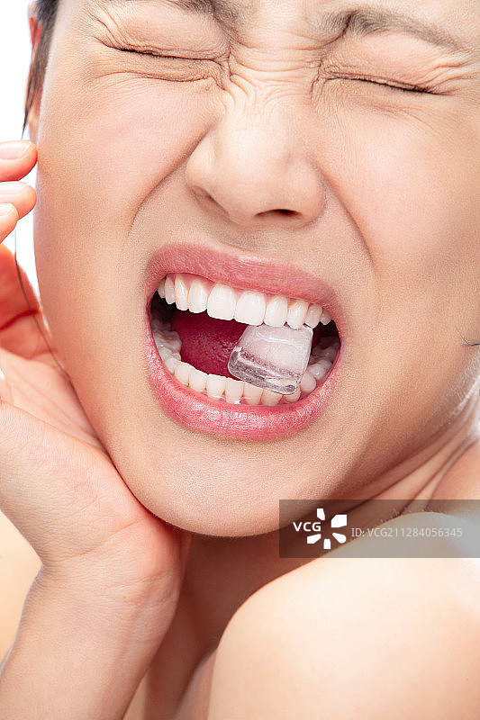 咬着冰块突然牙疼的青年女人图片素材