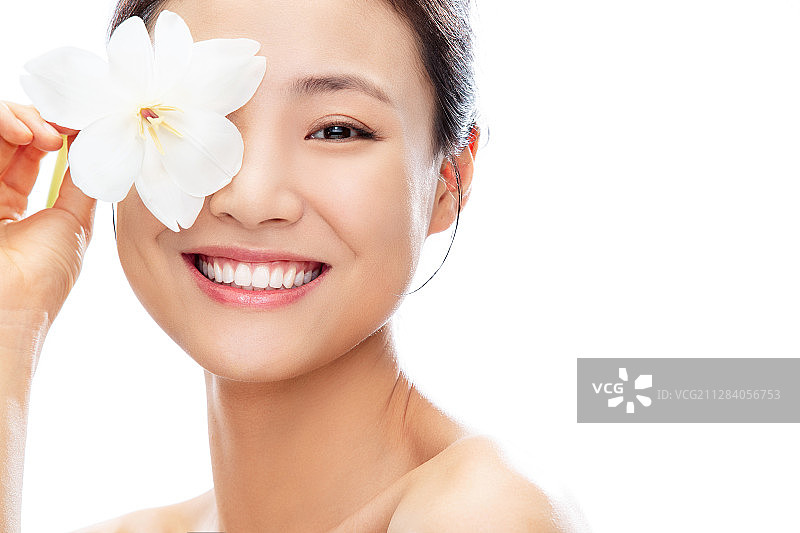 用芍药花挡住一只眼睛的青年女人图片素材