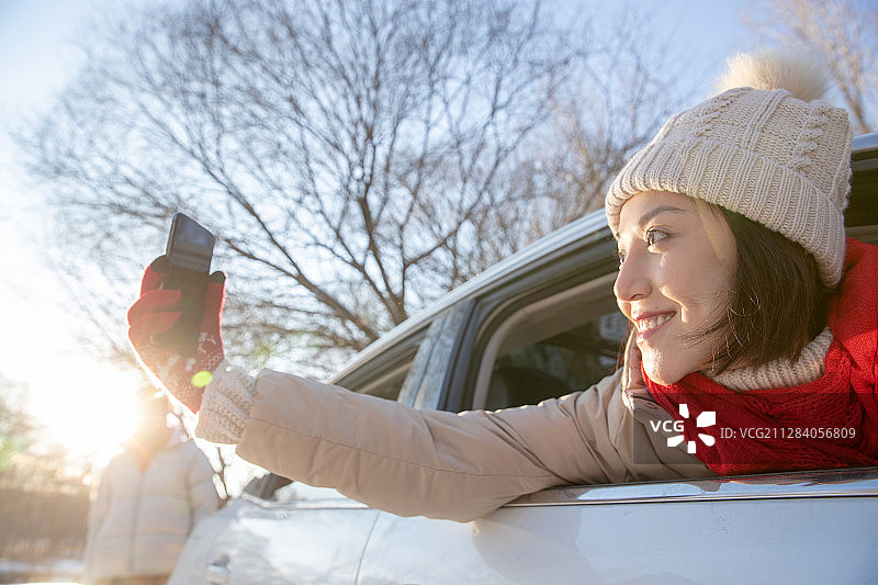 年轻女人坐在汽车里看手机图片素材