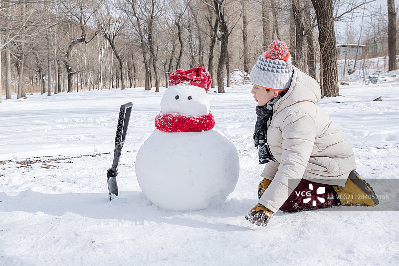 快乐的小男孩在雪地里堆雪人图片素材