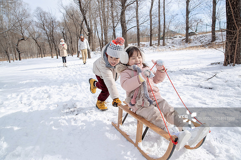 欢乐家庭在雪地上玩雪橇图片素材
