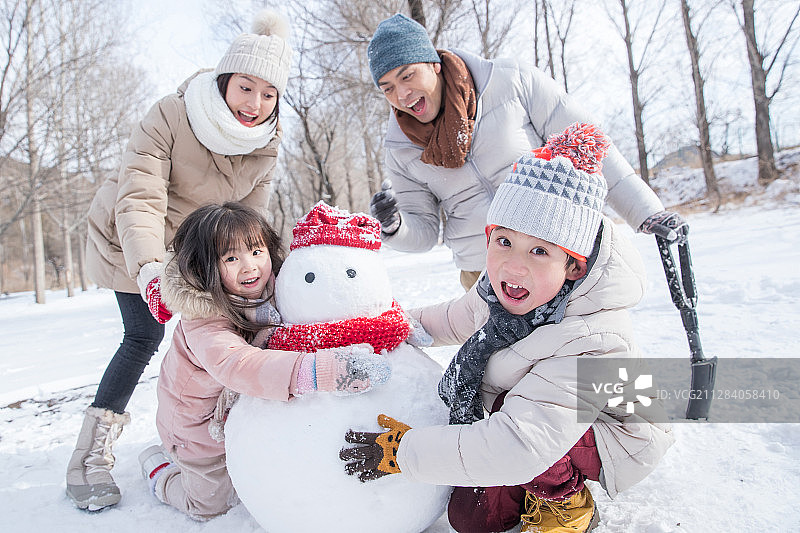 欢乐家庭在雪地里堆雪人图片素材