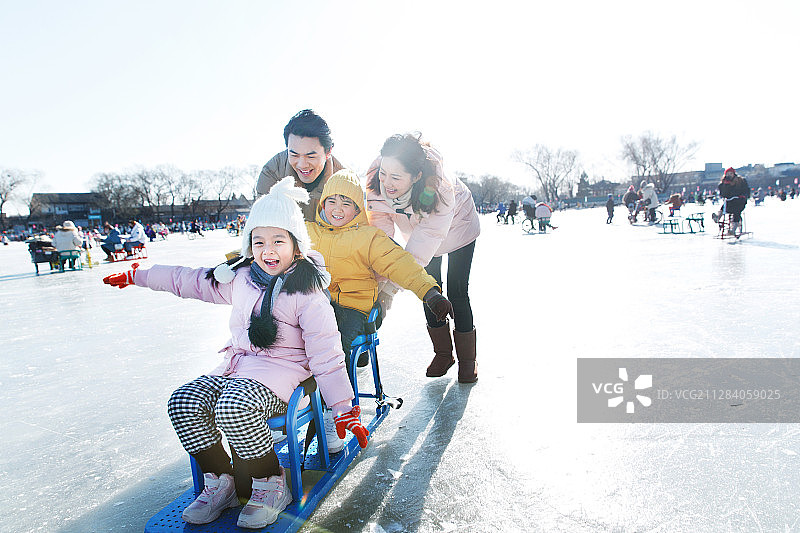 快乐的一家四口坐冰车玩耍图片素材