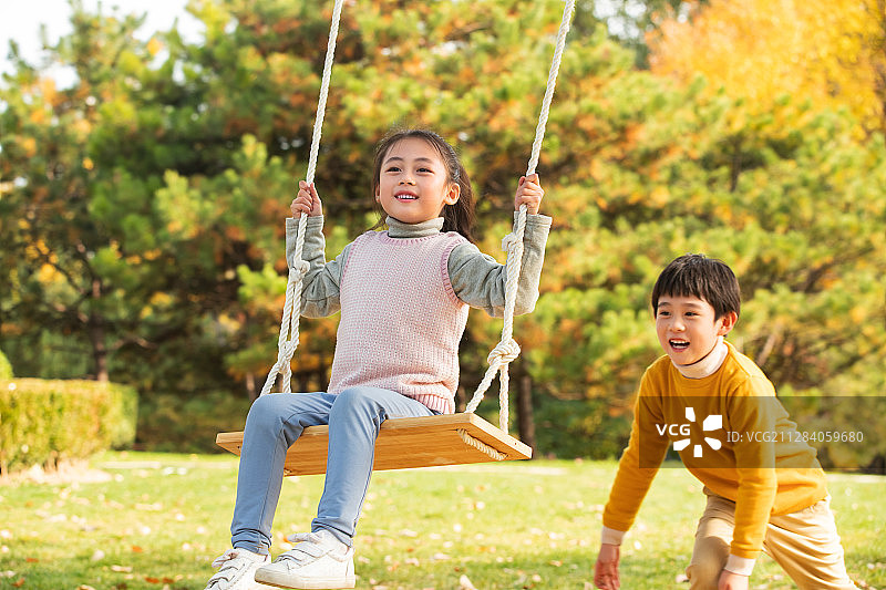 在公园里荡秋千的快乐儿童图片素材