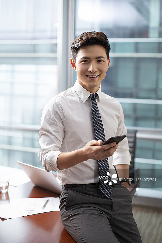 自信的商务男士在办公室使用手机图片素材