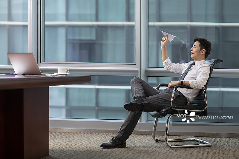 自信的商务男士在办公室扔纸飞机图片素材