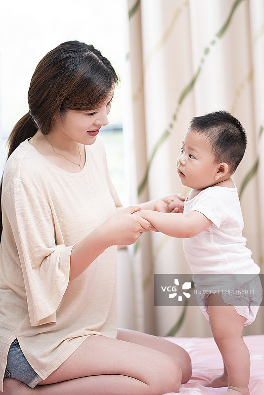 年轻妈妈和婴儿在床上玩耍图片素材