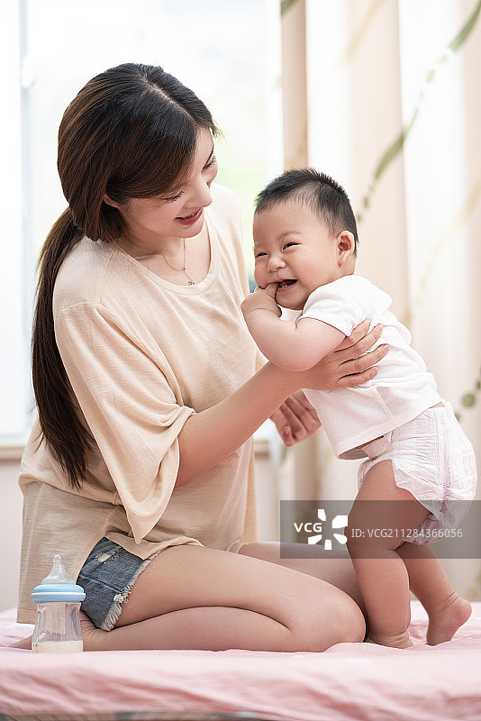 年轻妈妈和婴儿在床上玩耍图片素材