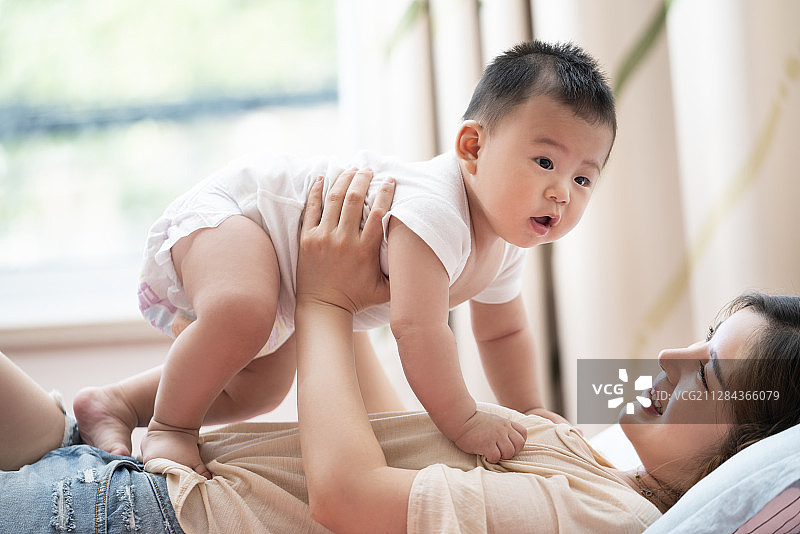 年轻妈妈和婴儿在床上玩耍图片素材