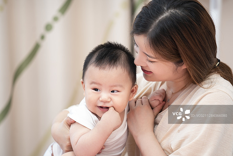 年轻妈妈和婴儿在床上玩耍图片素材