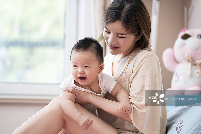 年轻妈妈和婴儿在床上玩耍图片素材