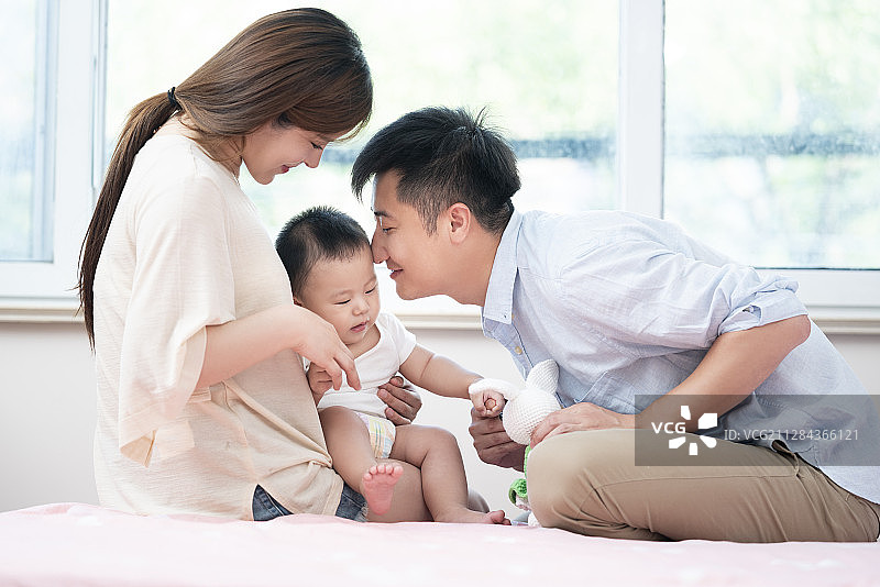 年轻父母在床上和婴儿玩耍图片素材