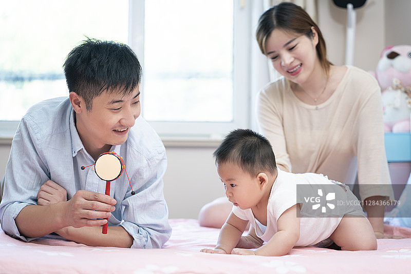 年轻父母在床上和婴儿玩耍图片素材