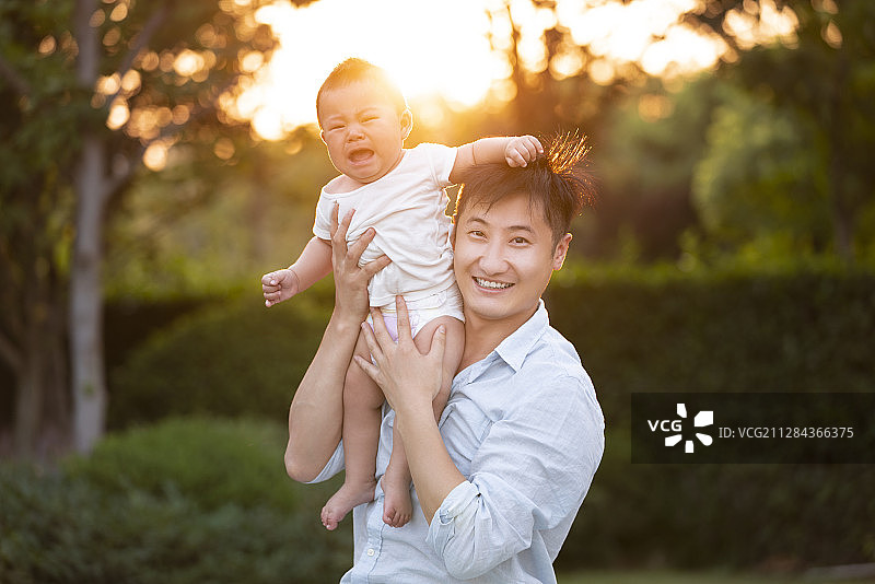 年轻爸爸举起婴儿玩耍图片素材