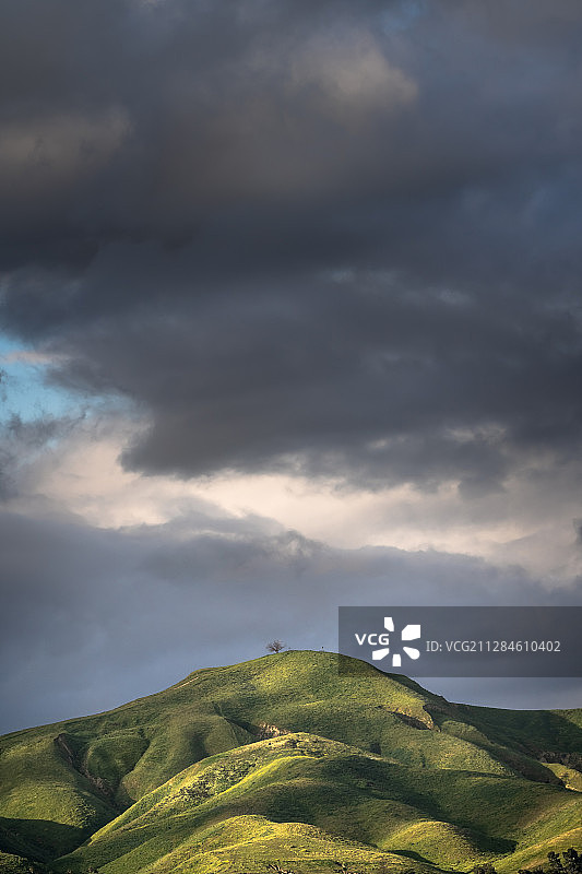 美国文图拉黑暗天空下阳光照耀的绿色山丘图片素材