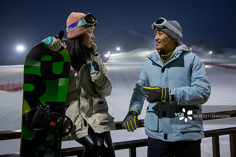 夜晚坐在护栏上聊天的青年伴侣图片素材