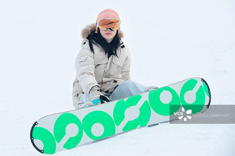 踩着单板坐在雪地上的青年女人图片素材