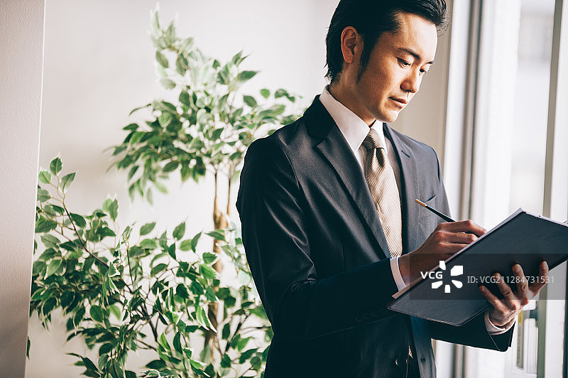男老板在窗边记录文件图片素材