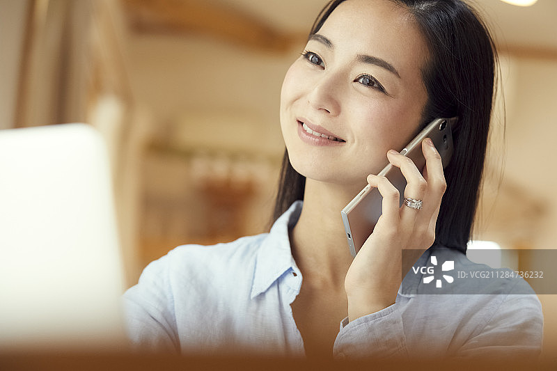 母亲在客厅工作时打电话图片素材