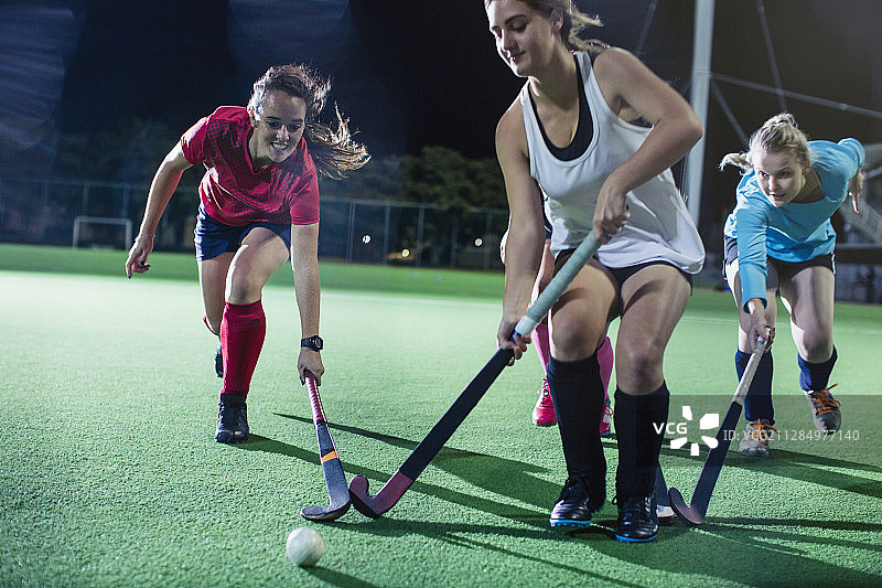 年轻女子在夜间球场上进行曲棍球比赛图片素材