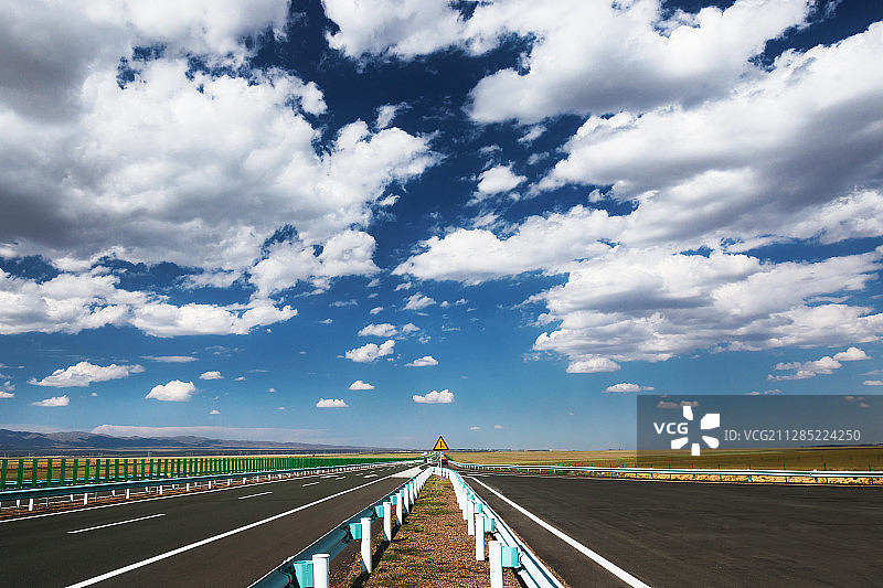 蓝天白云下平原上的的高速公路与交通标志牌图片素材