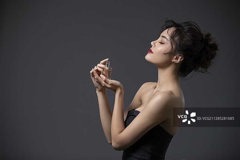 漂亮的年轻女士喷香水图片素材